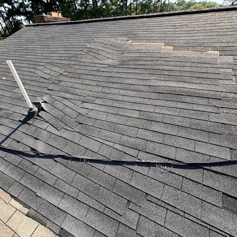 Asphalt shingle roof with lifted and missing shingles