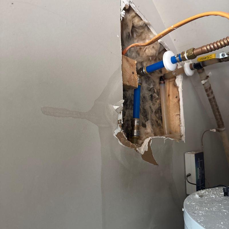 Water supply pipe leak behind drywall with water damage stain