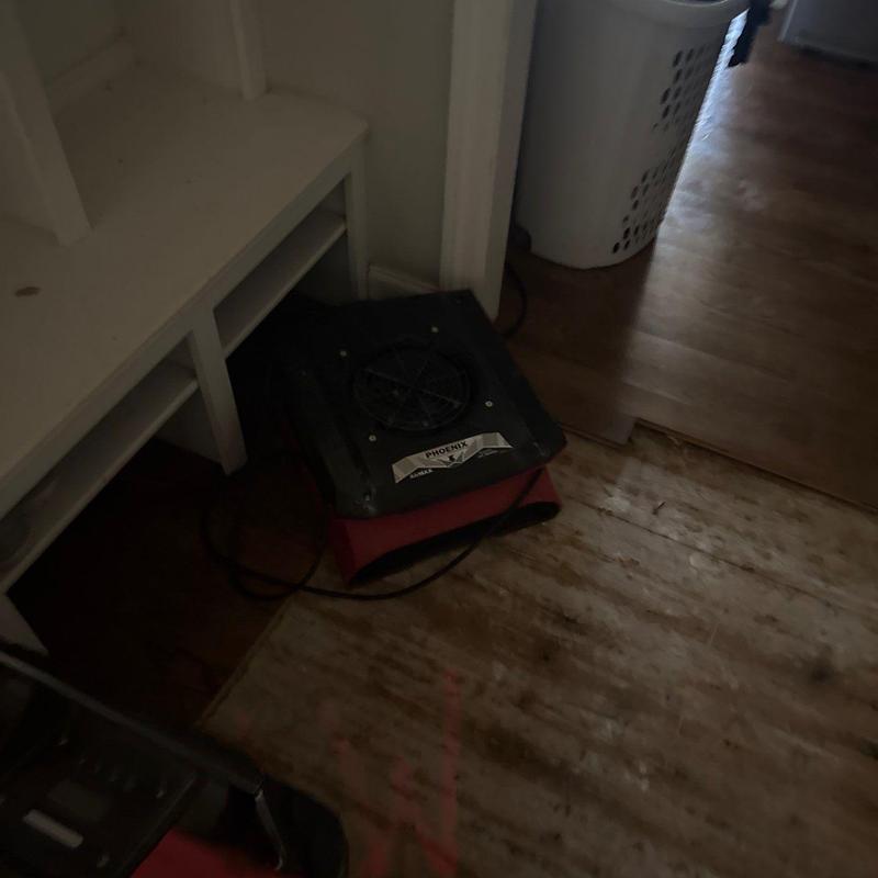Air mover on damaged hardwood floor in hallway