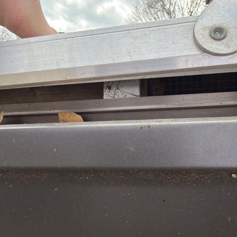 Roof shingles and flashing with hail damage on ladder edge