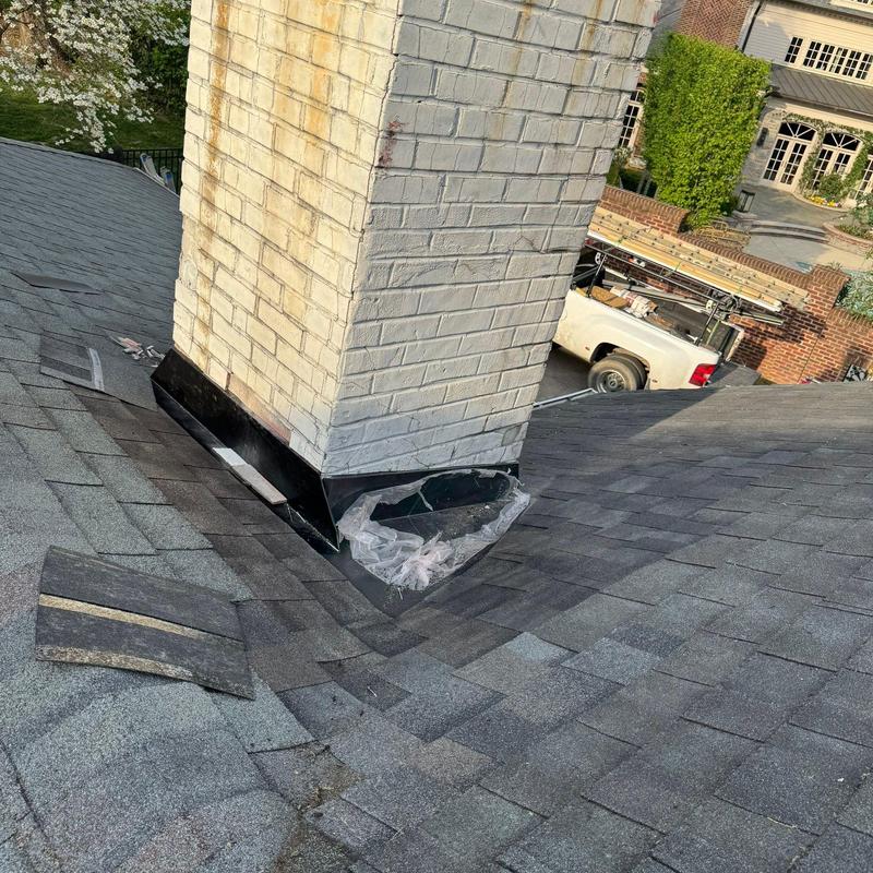 Chimney flashing and shingle damage on roof slope