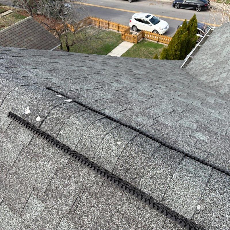 Asphalt shingle roof with hail damage near ridge ventilation