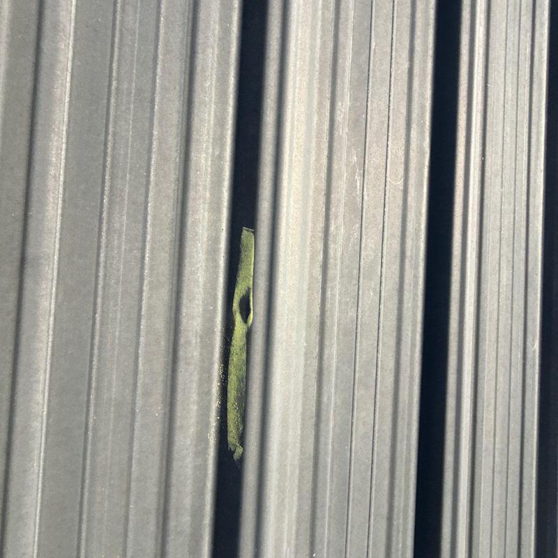 Metal roofing panel with hail damage hole marked