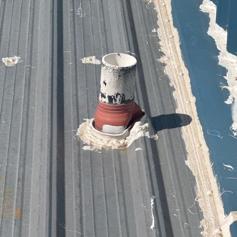 Roof pipe flashing with sealant on metal roof panel