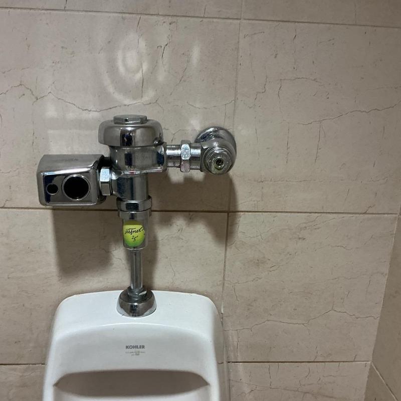 Urinal flush valve and sensor assembly on tiled wall Urinal flush valve and sensor assembly on tiled wall