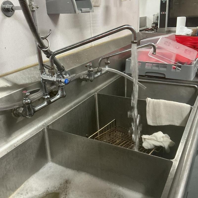 Commercial kitchen faucet with lever handle flowing water Commercial kitchen faucet with lever handle flowing water