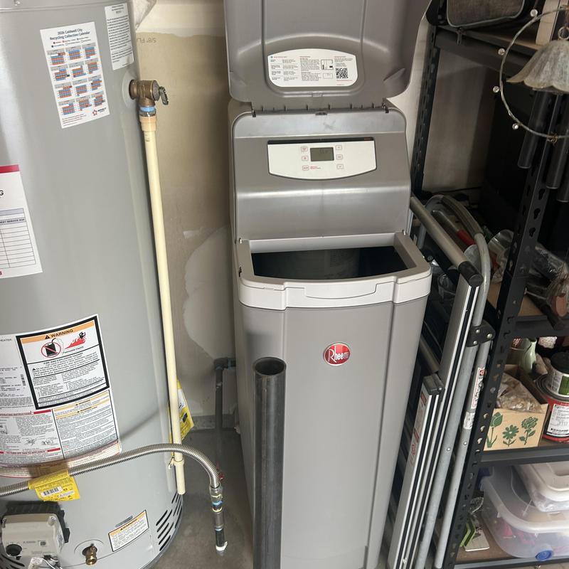 Water softener system with open control panel indoors Water softener system with open control panel indoors