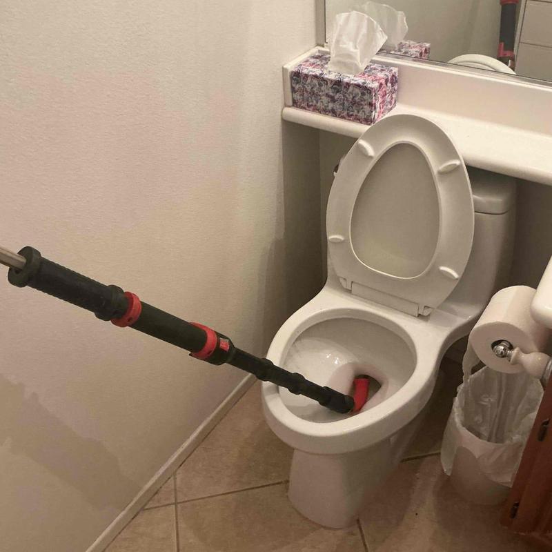 Toilet auger clearing blockage in bathroom bowl