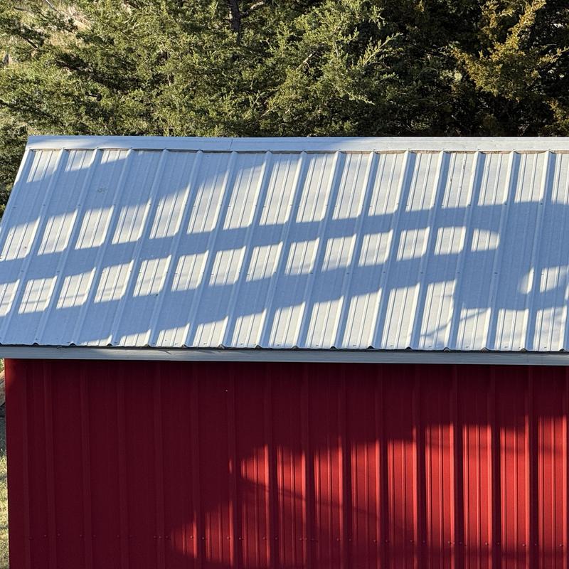 Metal roof panels on red shed with tree shadows Metal roof panels on red shed with tree shadows