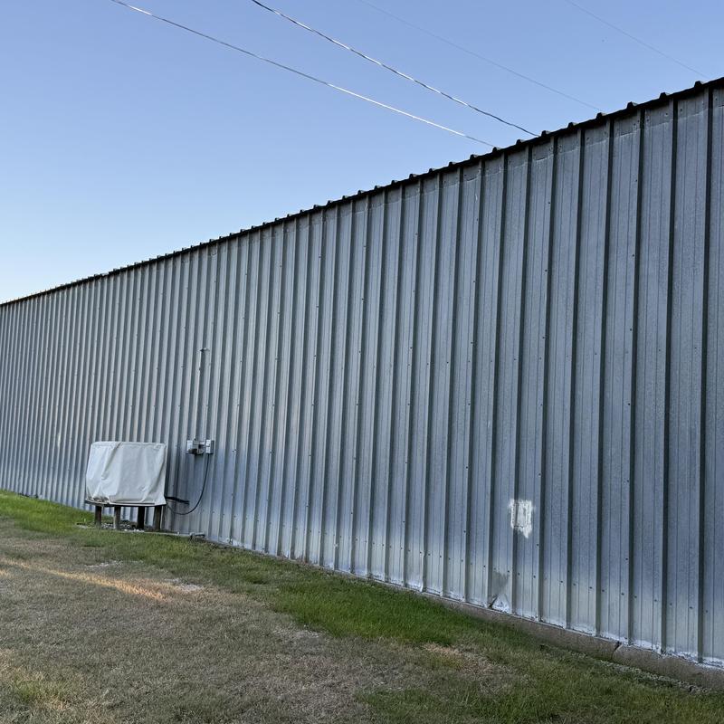 Metal building siding with electrical unit and grass lawn Metal building siding with electrical unit and grass lawn