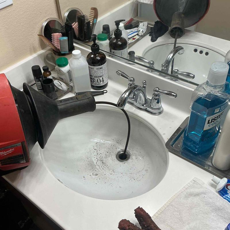 Bathroom sink drain line snaking with drain auger tool