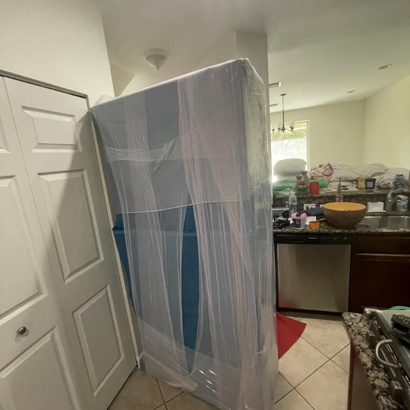 Baby grand piano wrapped for moving in kitchen