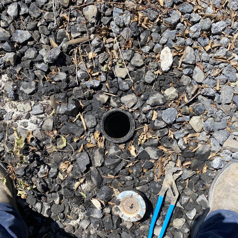 Grease trap discharge line cleanout with tools on gravel Grease trap discharge line cleanout with tools on gravel