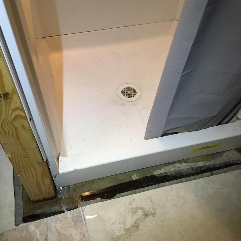 Shower pan with water leak and damaged floor tile
