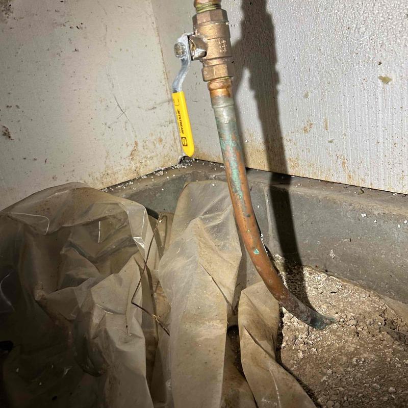 Irrigation shut off valve with yellow handle near wall