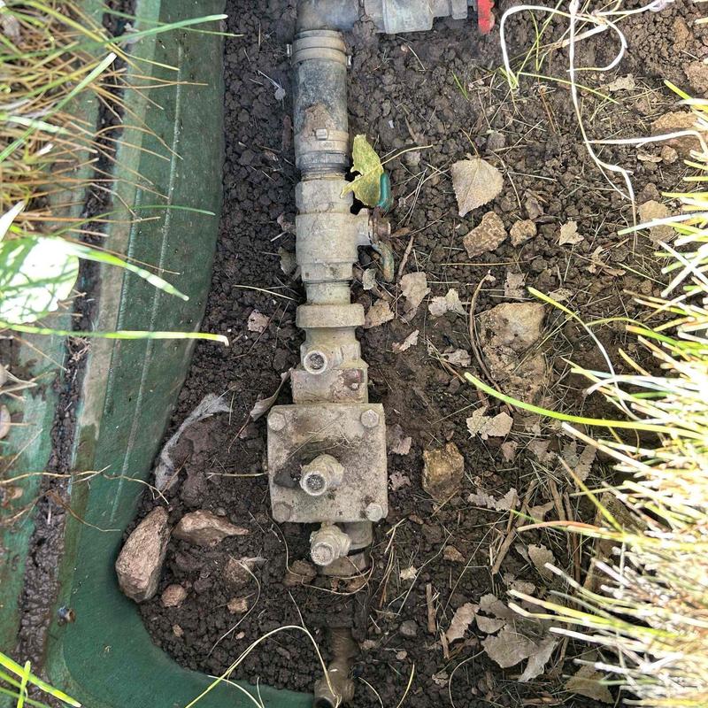 Irrigation water meter and shut-off valve exposed in soil