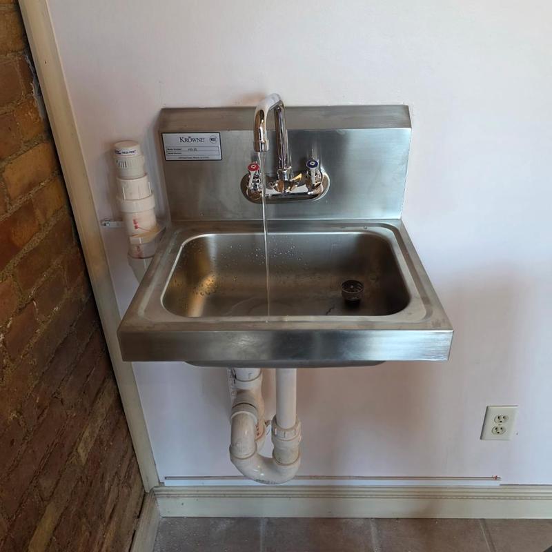 Three compartment stainless steel sink with faucet running Three compartment stainless steel sink with faucet running