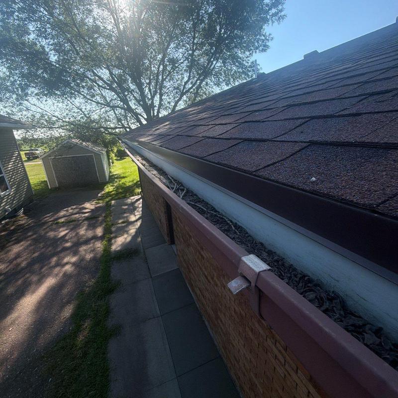 Roof shingles and debris-filled gutter on brick house Roof shingles and debris-filled gutter on brick house