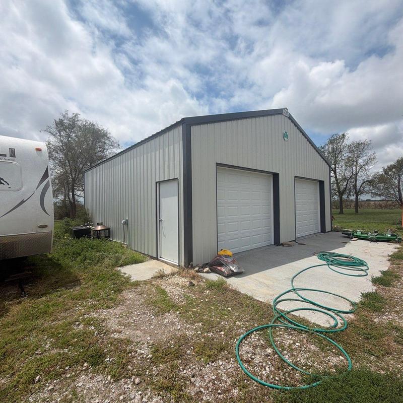 Metal garage exterior with concrete driveway and garden hose Metal garage exterior with concrete driveway and garden hose