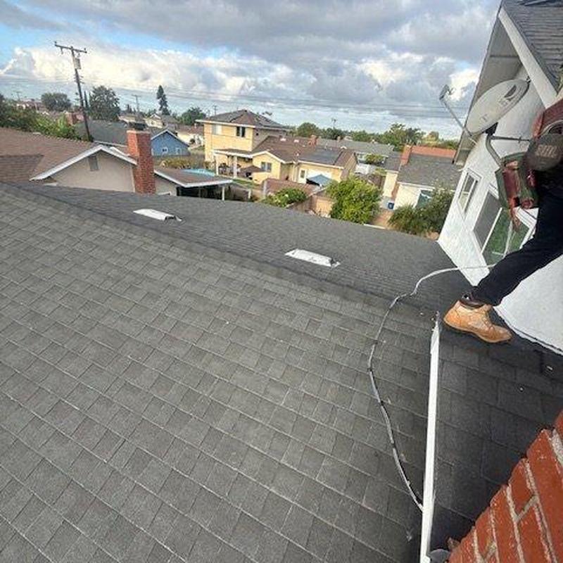 Shingle roof inspection with technician on edge Shingle roof inspection with technician on edge