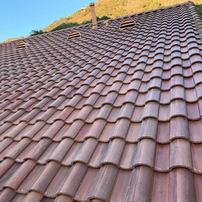 Tile roof with ventilation vents and hillside backdrop Tile roof with ventilation vents and hillside backdrop