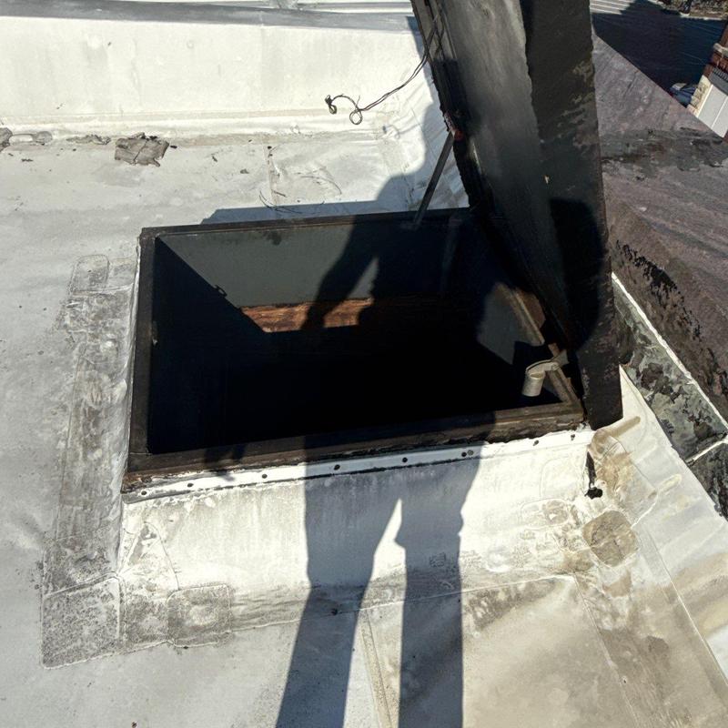 Roof hatch with open lid on flat roof surface