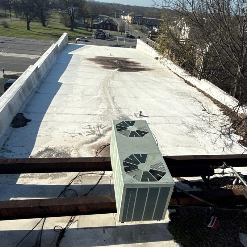 Flat roof with HVAC unit and roof damage spots