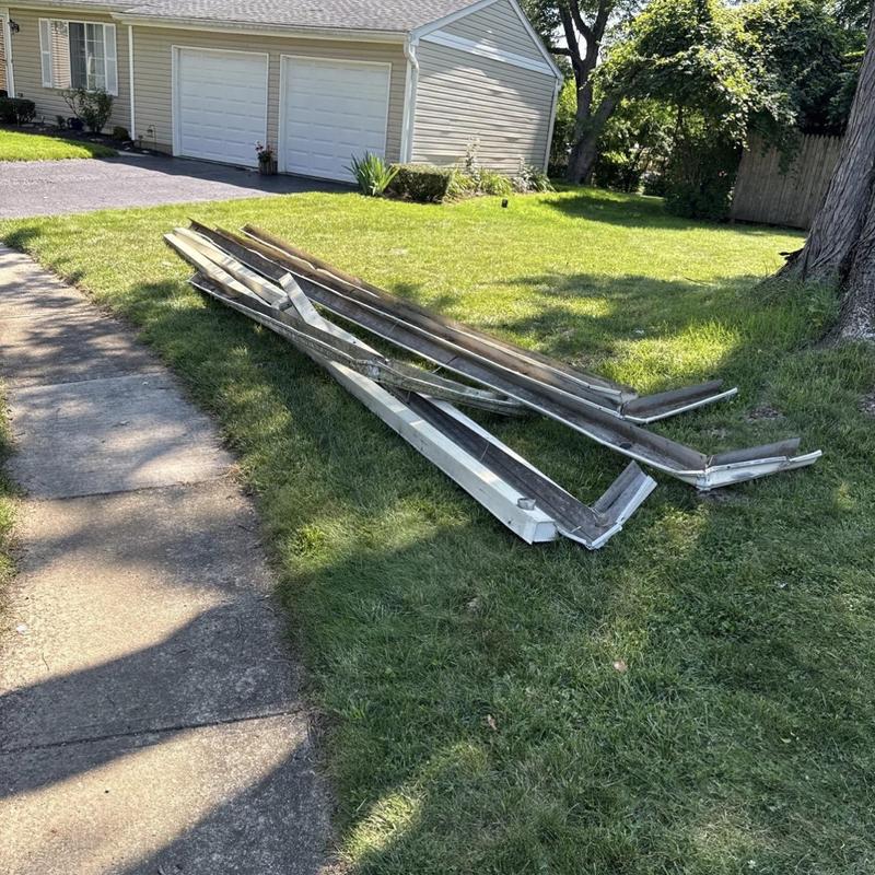 Seamless metal gutter sections on lawn near driveway Seamless metal gutter sections on lawn near driveway