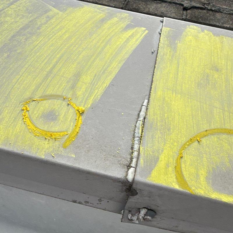 Metal roof panel hail damage marked with yellow paint