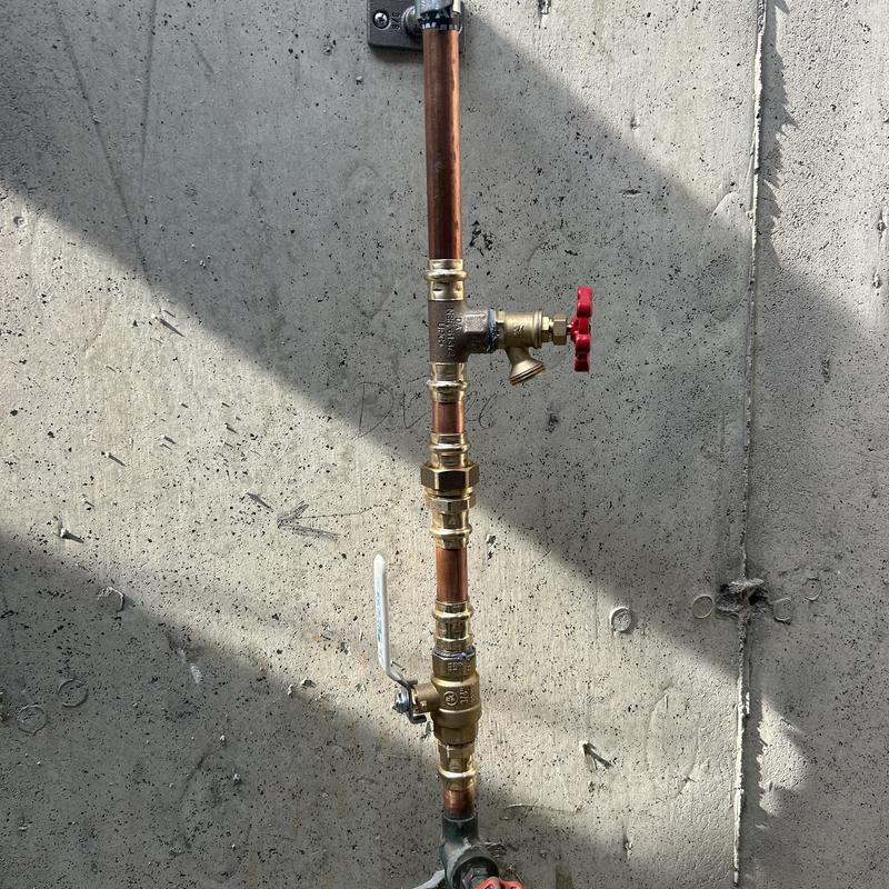 Copper piping with shut-off valves against concrete wall Copper piping with shut-off valves against concrete wall
