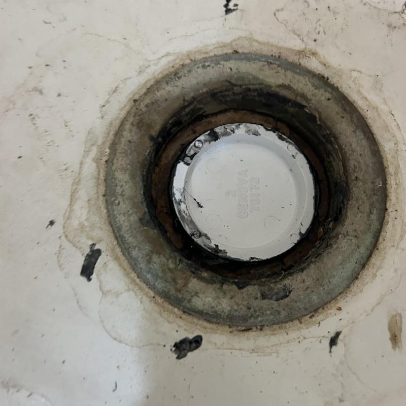 Pool drain cover with rusted metal fitting in floor Pool drain cover with rusted metal fitting in floor