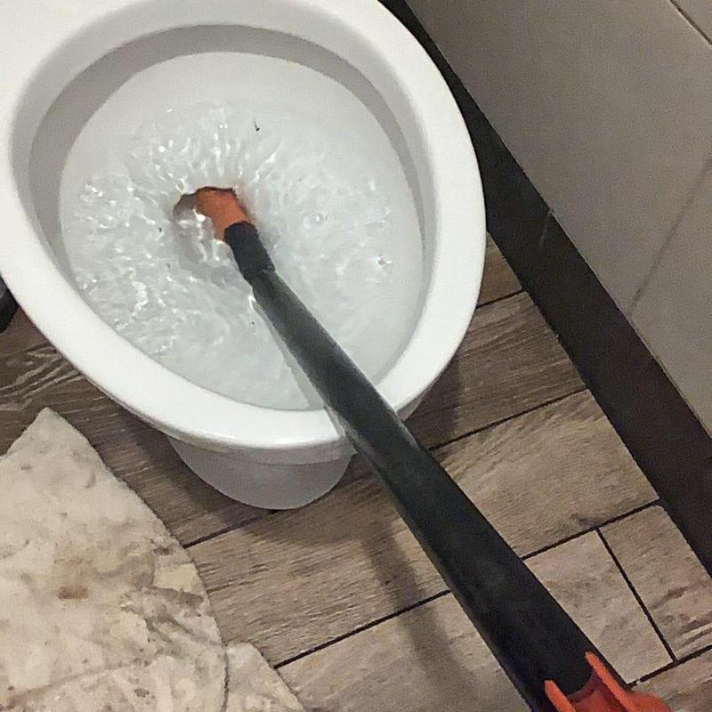 Commercial toilet auger clearing clog in restroom