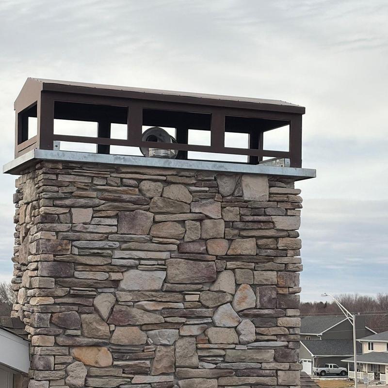 Chimney stonework with metal cap on residential roof Chimney stonework with metal cap on residential roof
