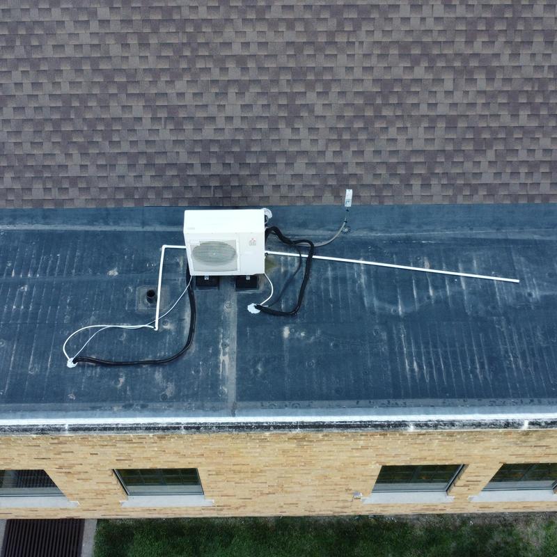 Rooftop HVAC condenser unit with wiring on flat roof Rooftop HVAC condenser unit with wiring on flat roof