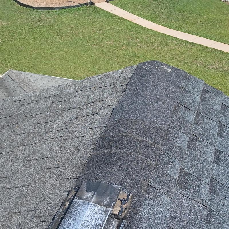 Ridge vent with storm-damaged shingles on roof