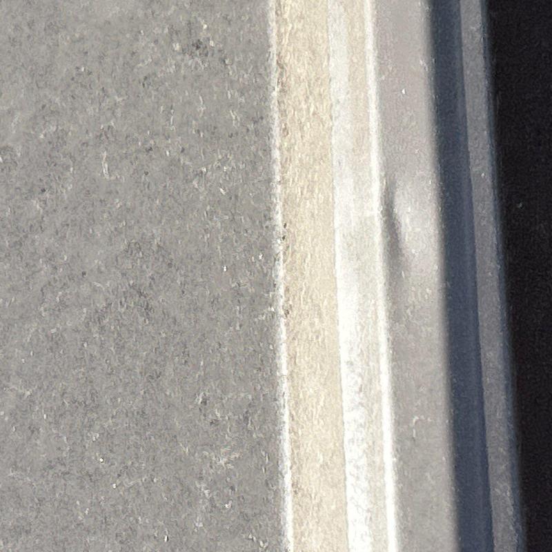 Roof metal flashing with hail damage dent