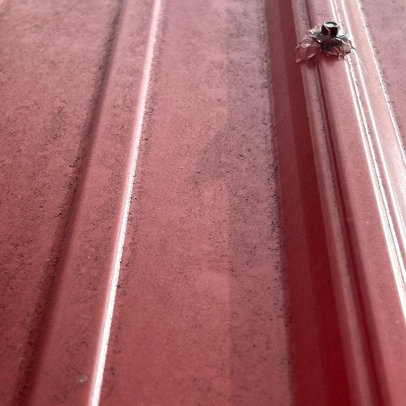 Metal roofing panel with hail damage dent