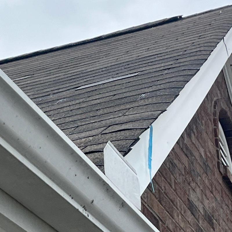 Asphalt shingle roof with hail damage near gutter and trim