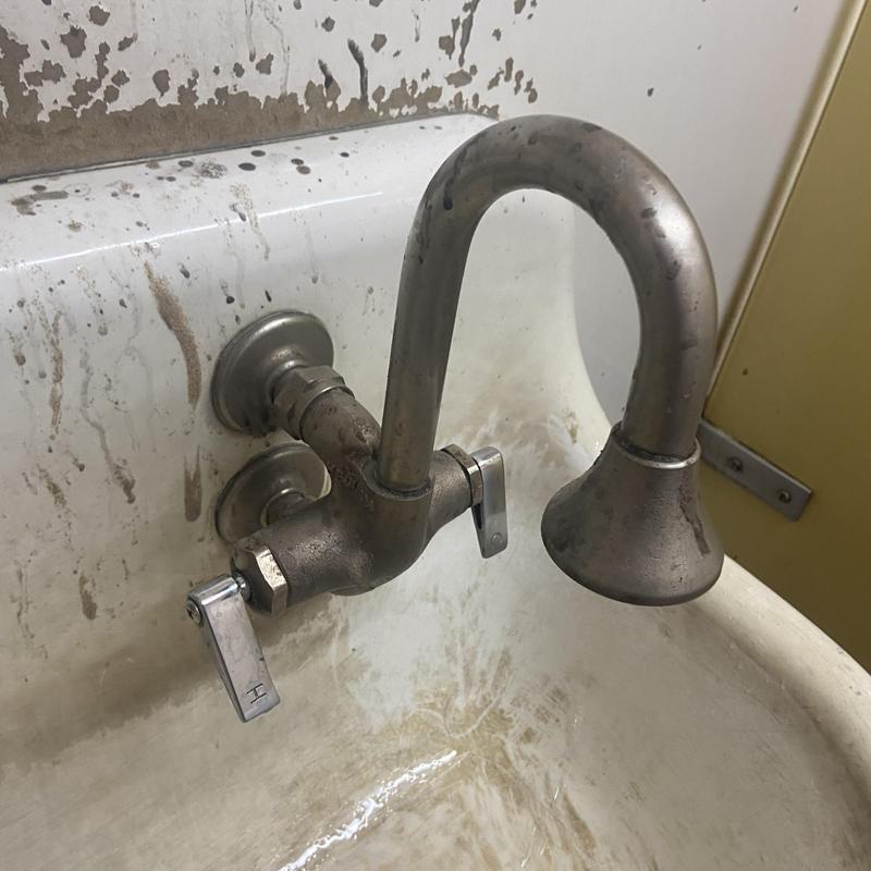 Wall-mounted faucet with worn sink basin and stained wall Wall-mounted faucet with worn sink basin and stained wall