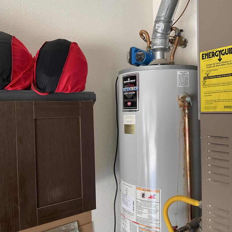 Water heater with rust stain and piping detail in garage Water heater with rust stain and piping detail in garage