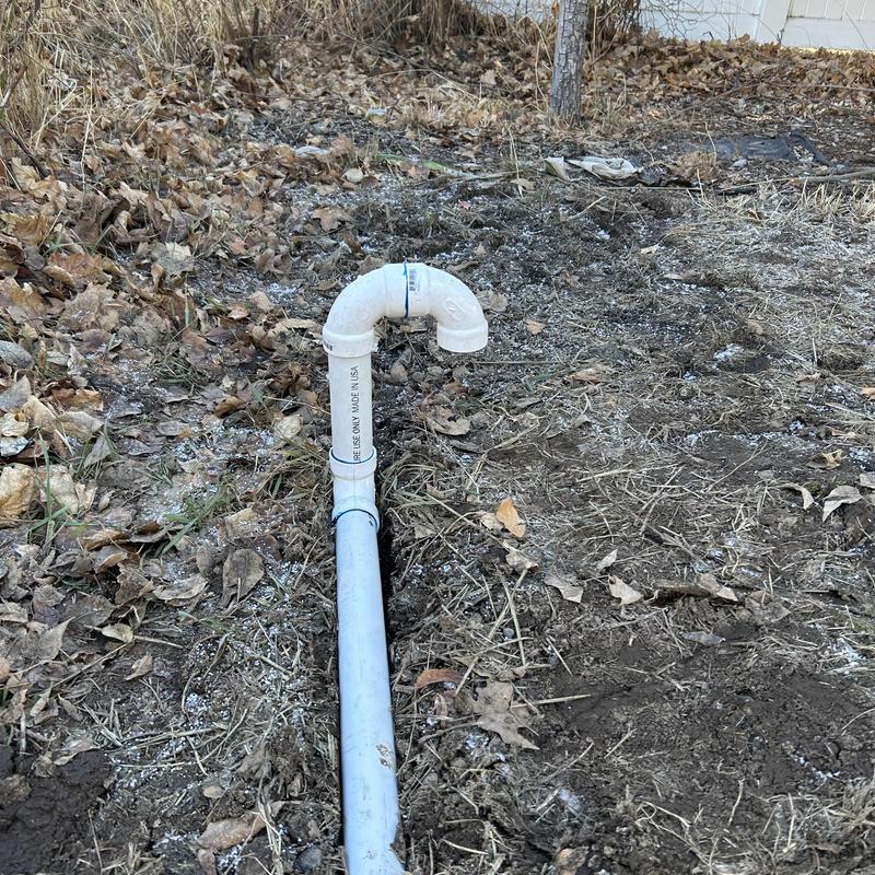 PVC sump pump drain line exposed in yard trench PVC sump pump drain line exposed in yard trench
