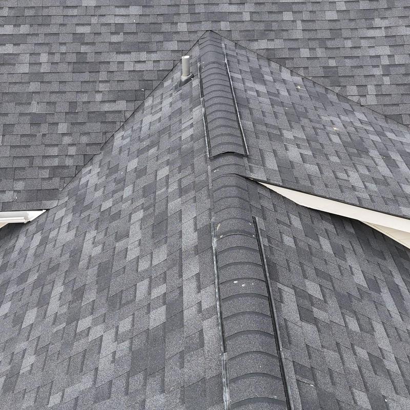 Asphalt shingle roof ridge with hail damage spots