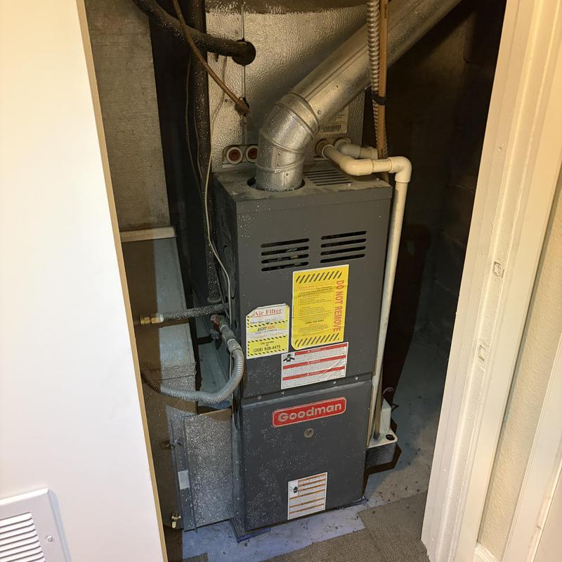 Furnace unit in utility closet with ventilation pipes Furnace unit in utility closet with ventilation pipes