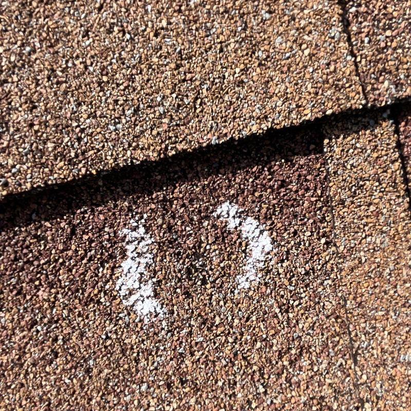 Hail-damaged asphalt roofing shingle with chalk mark