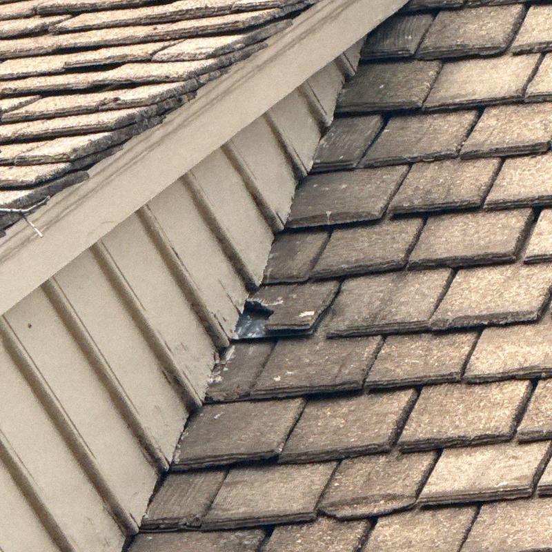 Roof shingles with visible hail damage near flashing