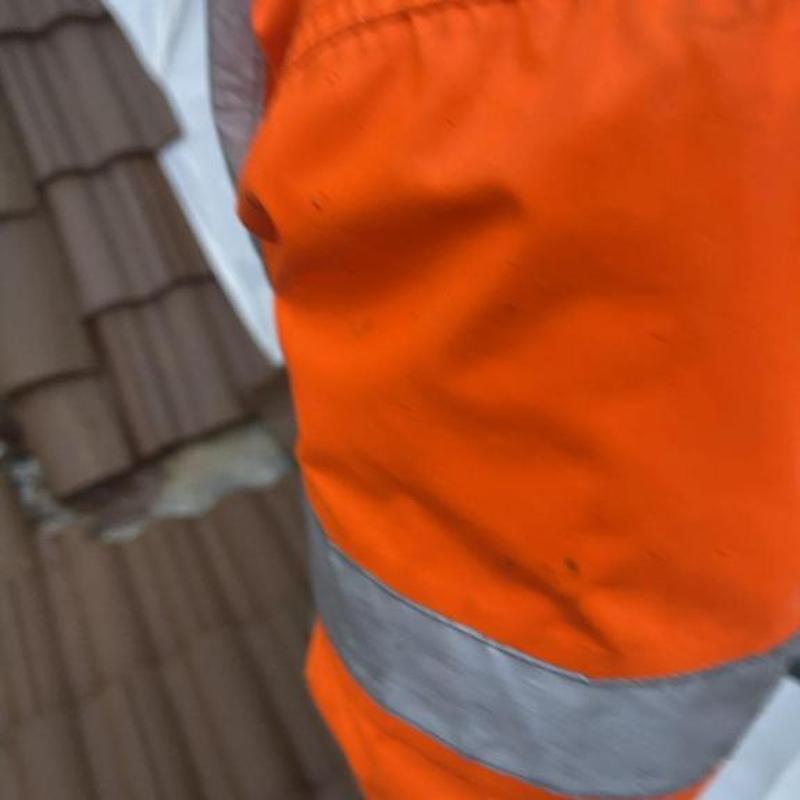 Clay tile roof with damaged tiles and worker gear Clay tile roof with damaged tiles and worker gear