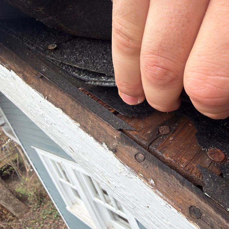Roof shingles lifted to inspect hail damage on wood deck
