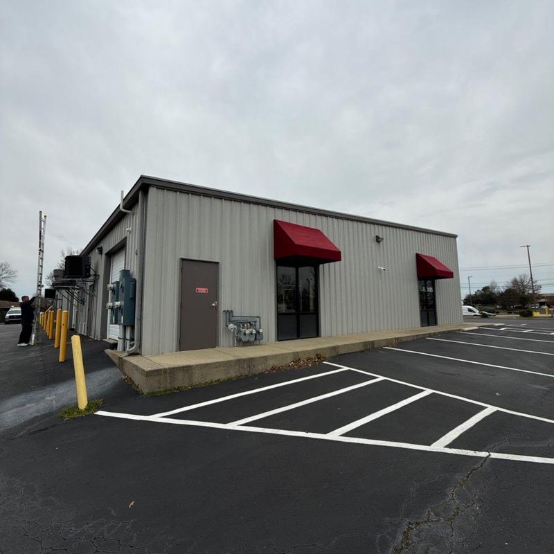 Metal building exterior with red awnings and parking lot