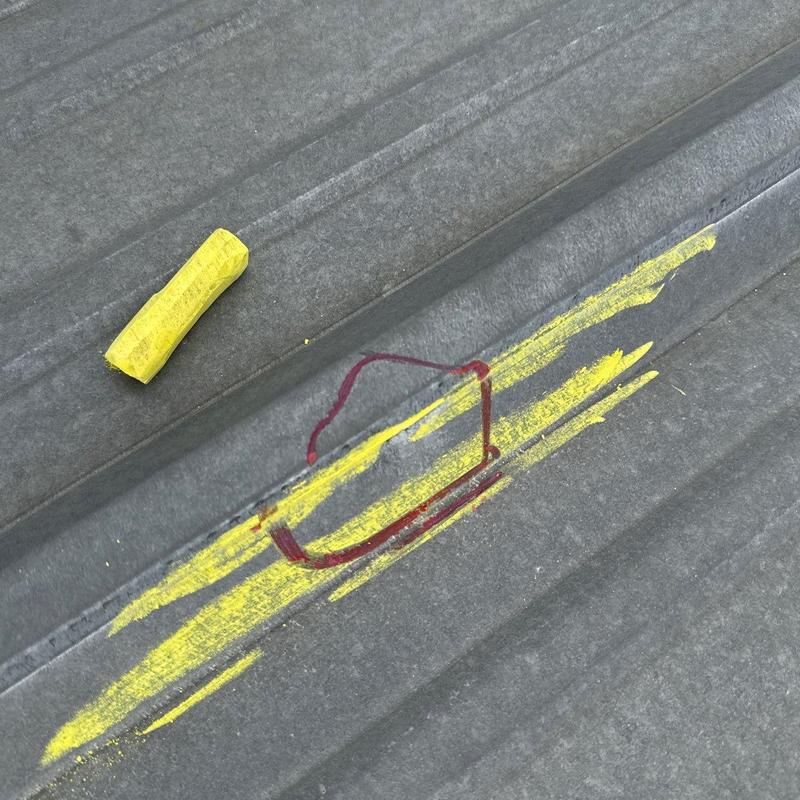 Metal roof panel hail damage marked for repair