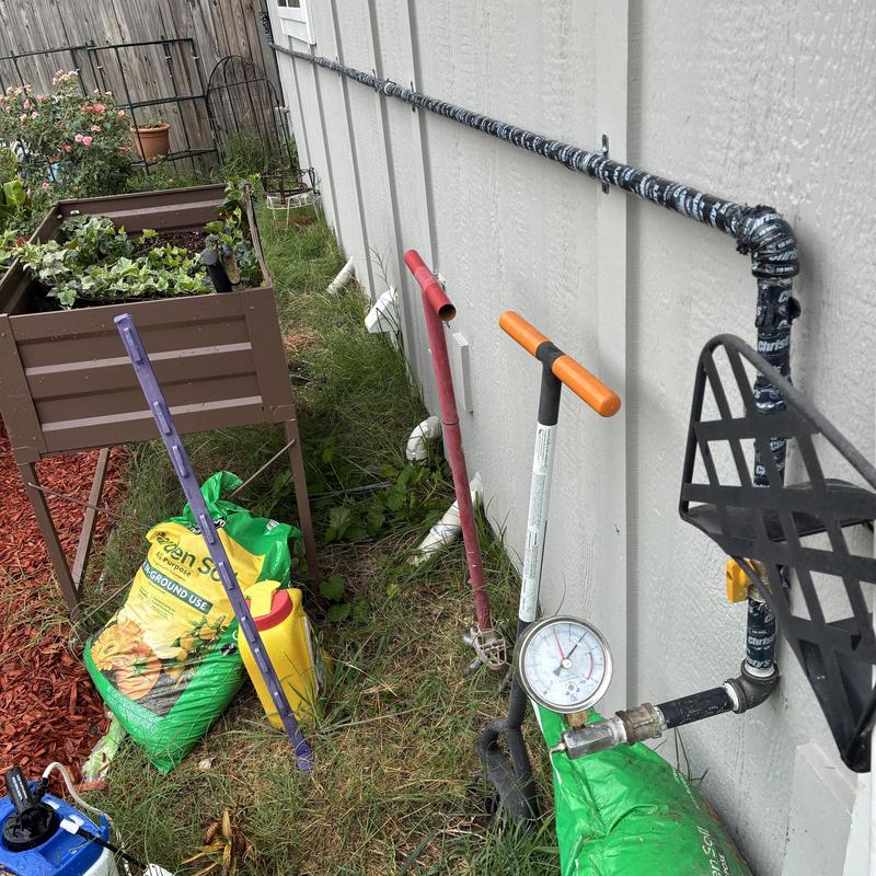 Black gas pipe installation with pressure gauge on exterior wall